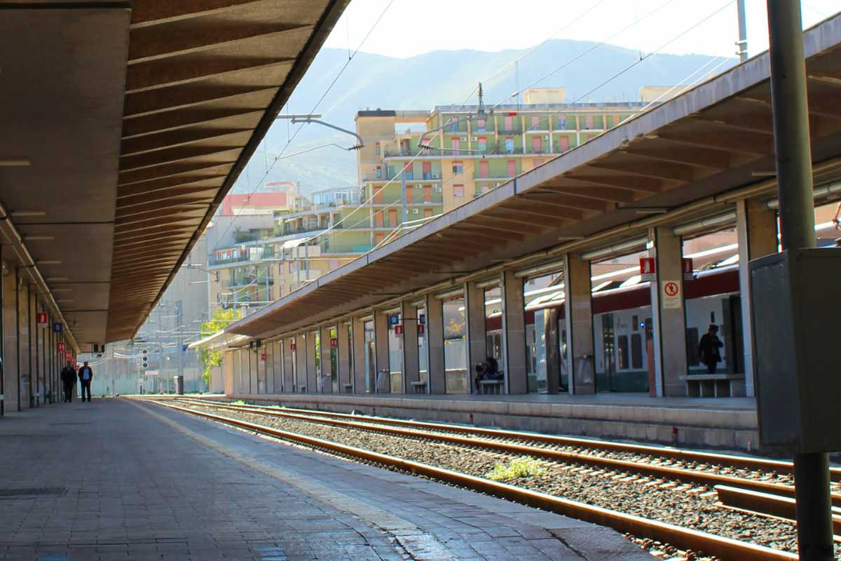 Interno di una stazione ferroviaria siciliana con treni in partenza