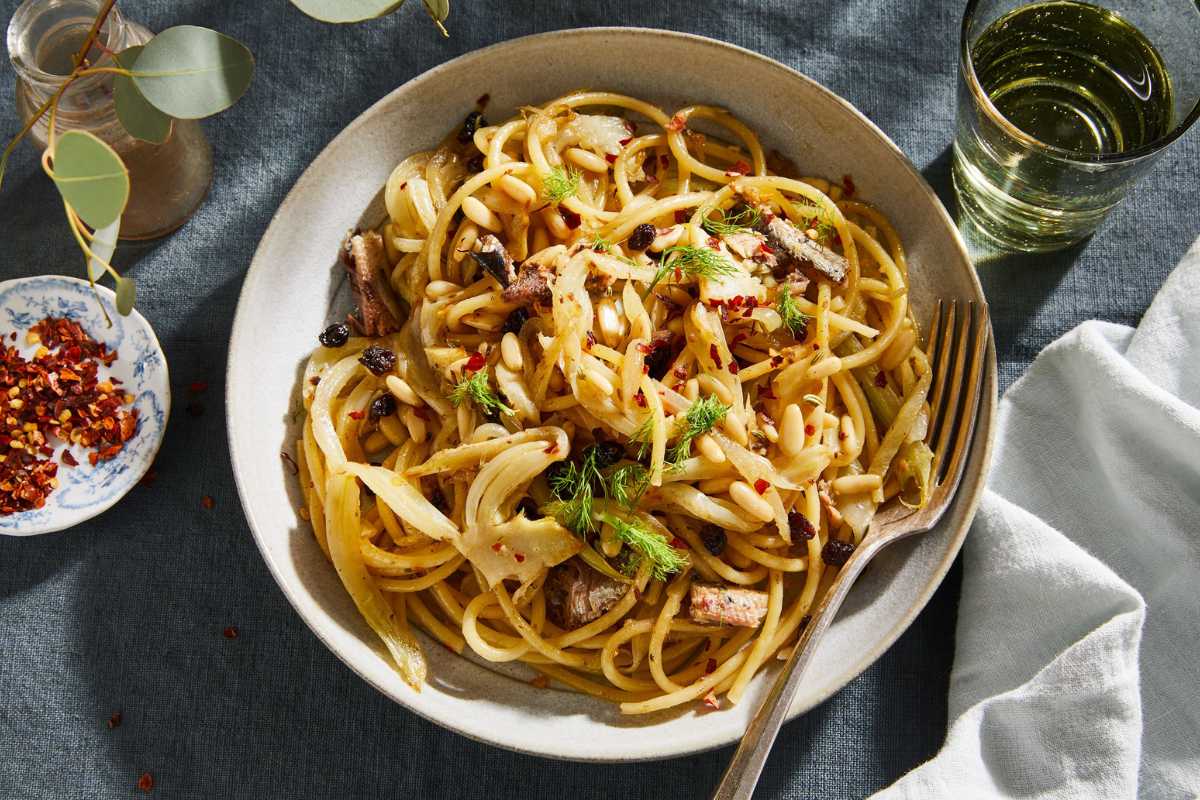 Piatto di pasta con le sarde servito su tavola mediterranea
