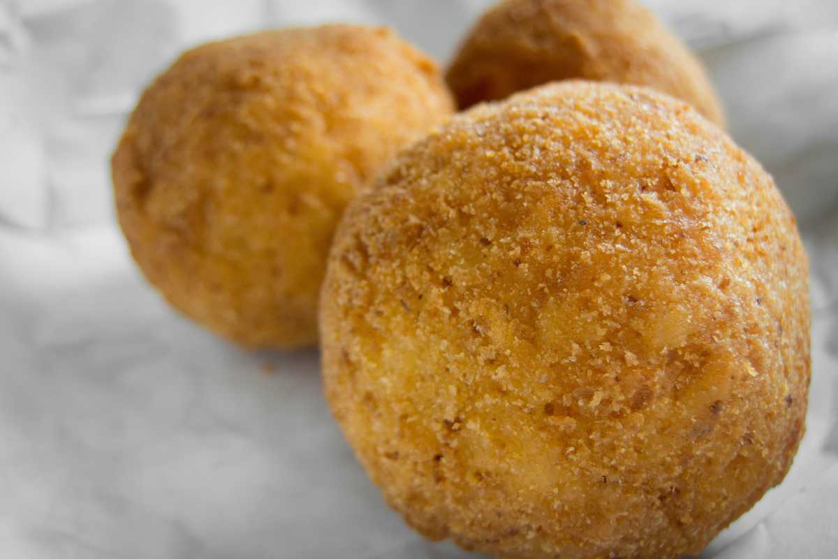 Piatto di arancini siciliani appena fritti su un tavolo di legno