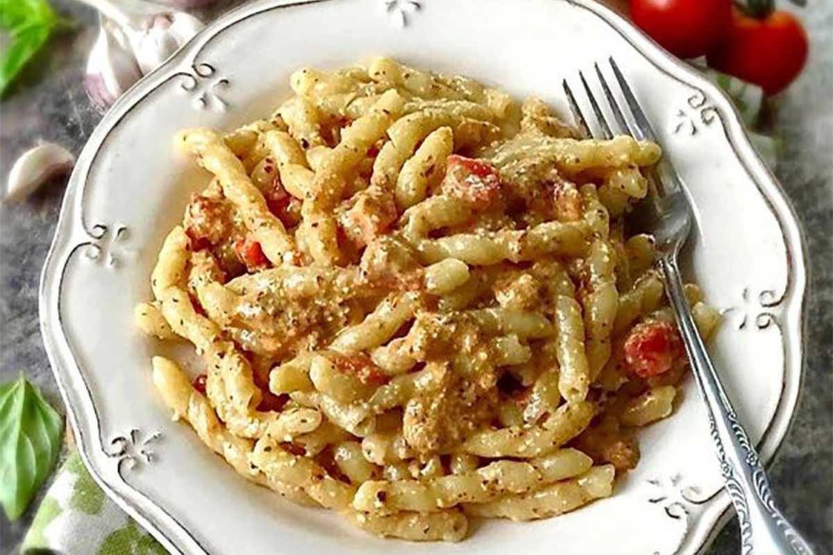 Un piatto di Busiate al pesto trapanese servito con ingredienti freschi